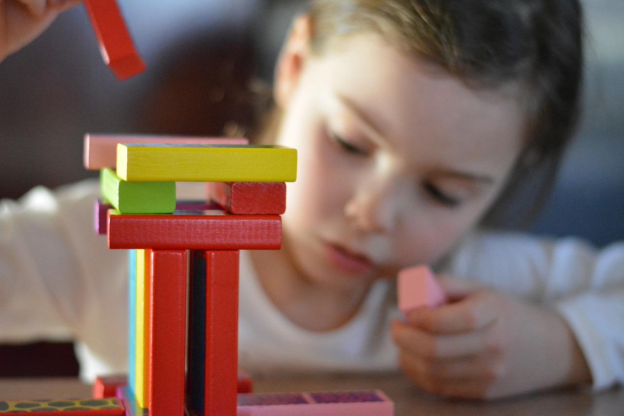 Girl playing and learning with building blocks at school