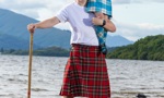 Young highland dancer on man in kilt shoulders at Loch Lomond