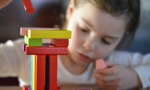 Young person building a tower with coloured wooden building blocks